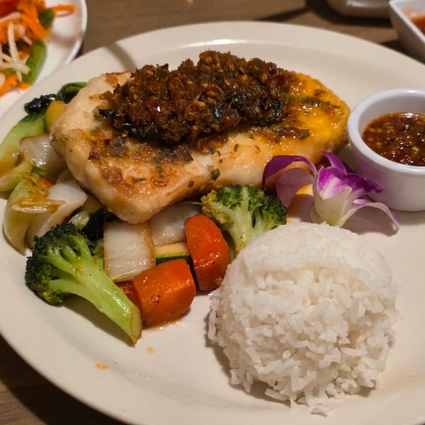 Pan-fried fish with chili sauce, steamed vegetables, white rice, and a side of dipping sauce.