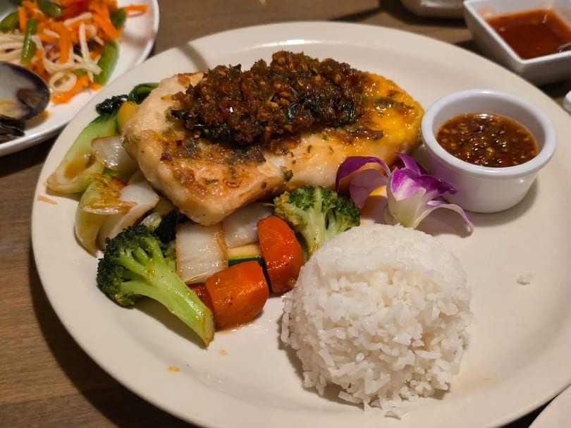 Pan-fried fish with chili sauce, steamed vegetables, white rice, and a side of dipping sauce.