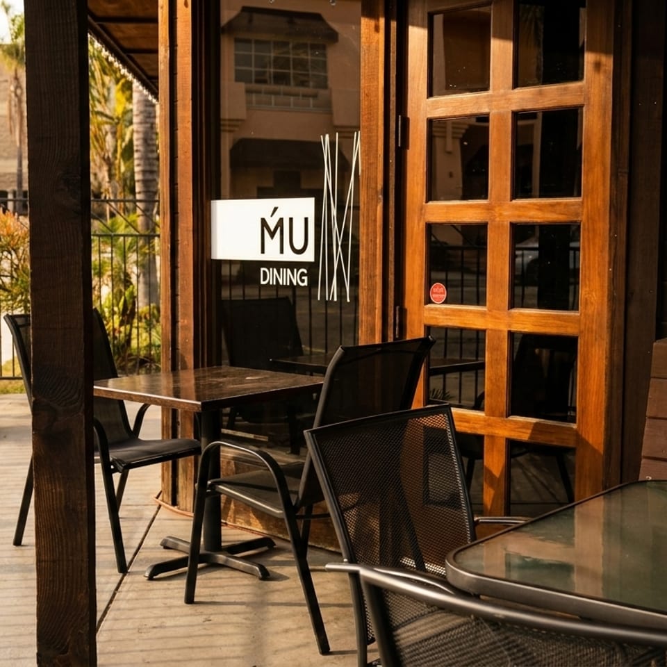 Outdoor patio of MU Dining with tables, chairs, and a wooden door with a sign.