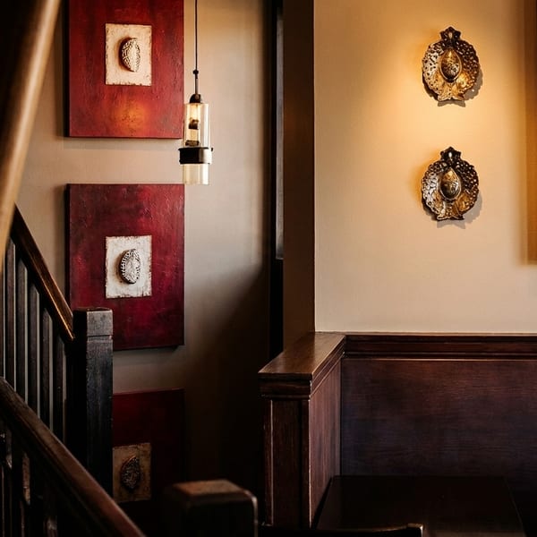 Restaurant interior with bamboo, dark wood railings, red and white art, and wall sconces.