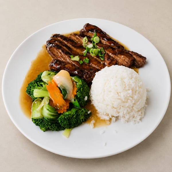 Grilled steak with sauce, white rice, and steamed vegetables on a white plate.
